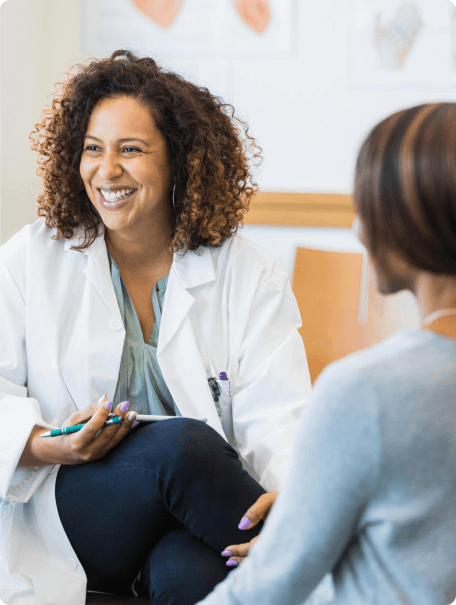 Female doctor with shoulder length curly hair smiles at a patient