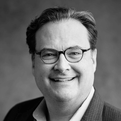 Black-and-white headshot of Lalan Wilfong, MD, wearing glasses and a suit jacket and smiling.