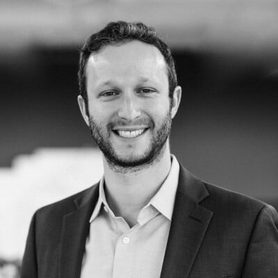 Black and white photo of Nate Brown with a warm smile and wearing a button down and blazer.